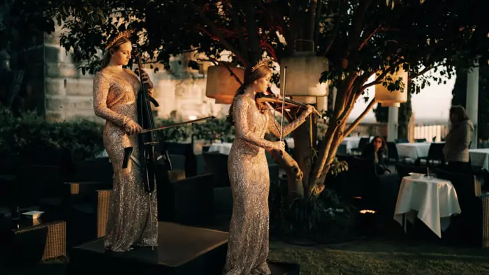 Two female violinists play, delighting guests at an elegant wedding | Mikevents