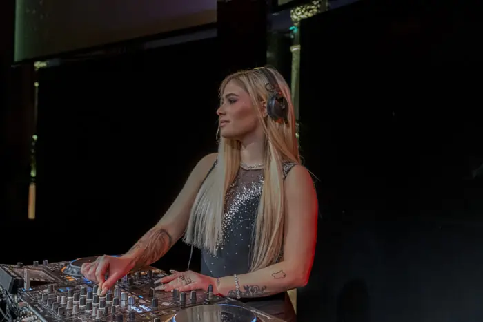 A female DJ at the console during an elegant wedding party | Mikevents
