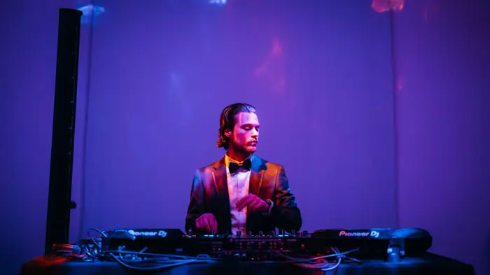 A DJ at his booth during an elegant wedding celebration | Mikevents