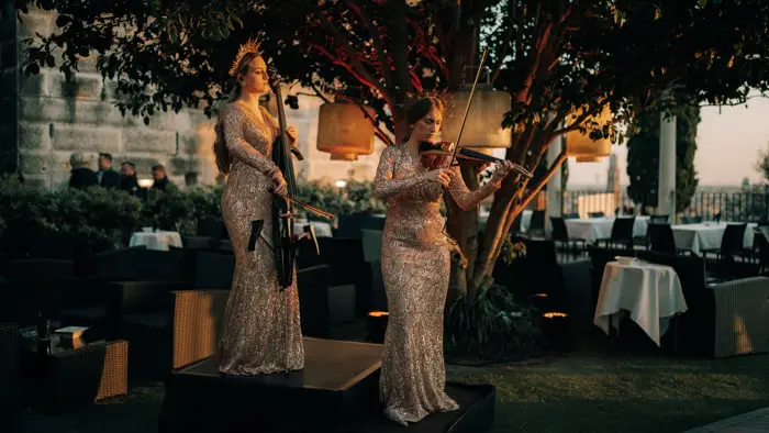 Two violinists perform at a wedding reception in a striking outdoor venue | Mikevents