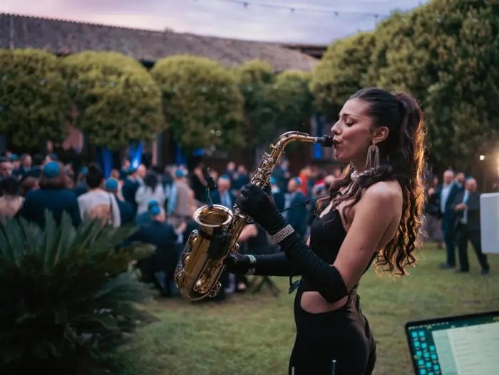 A saxophonist plays at a Roman outdoor wedding on a beautiful lawn | Mikevents