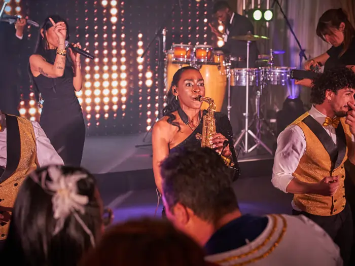 A saxophonist performs with the band at a corporate event | Mikevents