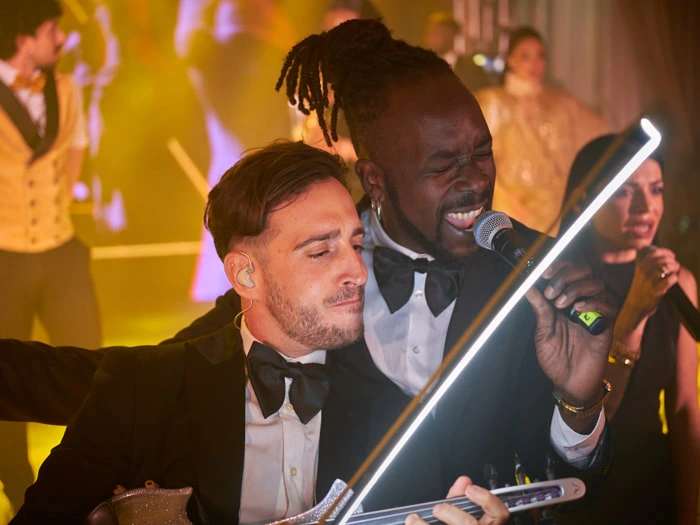 A violinist, a singer and a backing vocalist in the background perform during a corporate convention | Mikevents