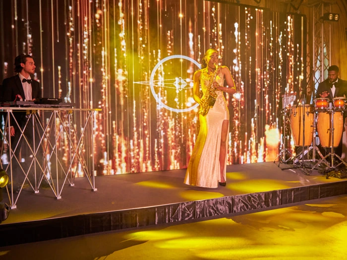 A saxophonist, a DJ and a percussionist perform during a corporate party | Mikevents