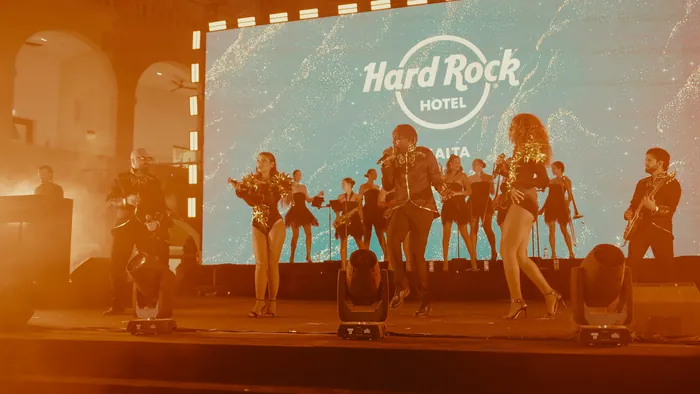 Big band and singers on stage in front of a giant screen showing the Hard Rock Hotel Malta logo | Mikevents
