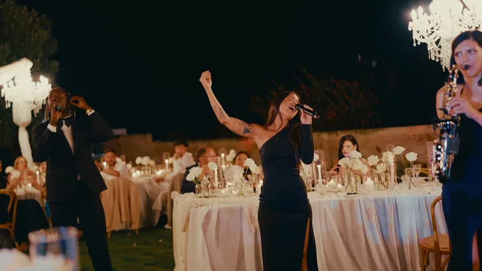 Singer performing among the tables at a wedding dinner, with live sax | Mikevents