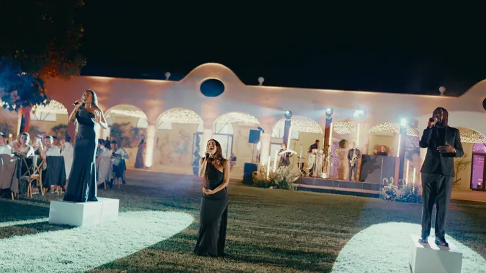 Three singers on white platforms on the lawn, in front of the dinner tables at a villa | Mikevents