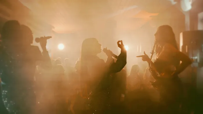 Singers and a saxophonist among the guests on the dance floor, in warm light and stage haze | Mikevents
