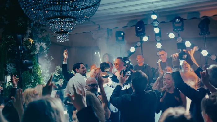 Guests dancing under a crystal chandelier as a saxophonist and a singer perform live | Mikevents