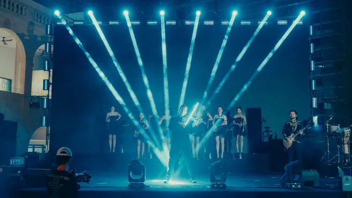 Violinist at center stage amid beams of blue light, with the big band lined up behind | Mikevents